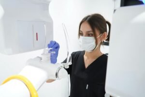 Maskeli diş sağlığı uzmanı, modern bir röntgen cihazını kullanıyor
