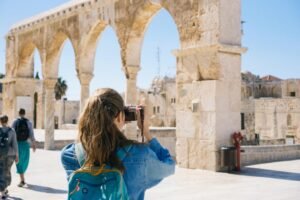 Antik taş kemerlerin önünde fotoğraf çeken kadın turist – turizm dijital pazarlama