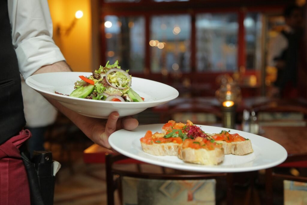 Restoranda garsonun servis ettiği salata ve bruschetta tabakları